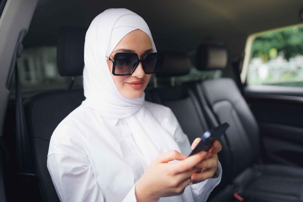 Woman in hijab using phone, intercity transfers in UAE